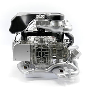 Ein detailliertes Modell eines Porsche 911 Turbomotors mit sichtbaren inneren Komponenten und Metallteilen, das fortschrittliche Turbotechnologie auf weißem Hintergrund präsentiert.