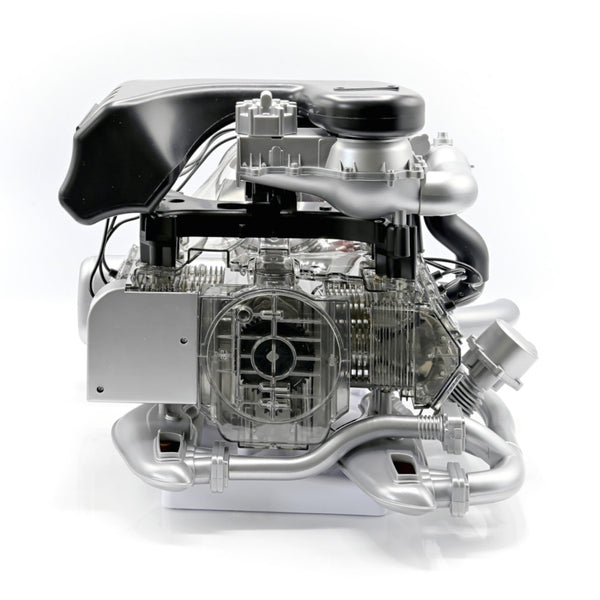 Ein detailliertes Modell eines Porsche 911 Turbomotors mit sichtbaren inneren Komponenten und Metallteilen, das fortschrittliche Turbotechnologie auf weißem Hintergrund präsentiert.