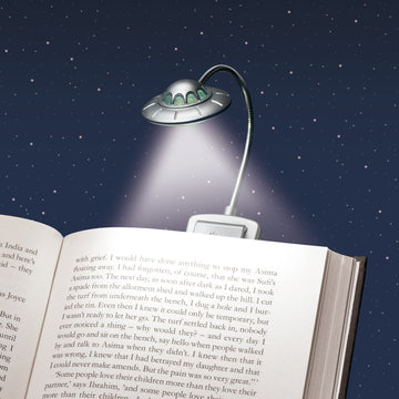 Eine UFO-förmige 3D-Leselampe beleuchtet ein offenes Buch vor einem sternenklaren Nachthimmel und erzeugt so ein außerirdisches Leselicht für Ihre nächtliche Lektüre.