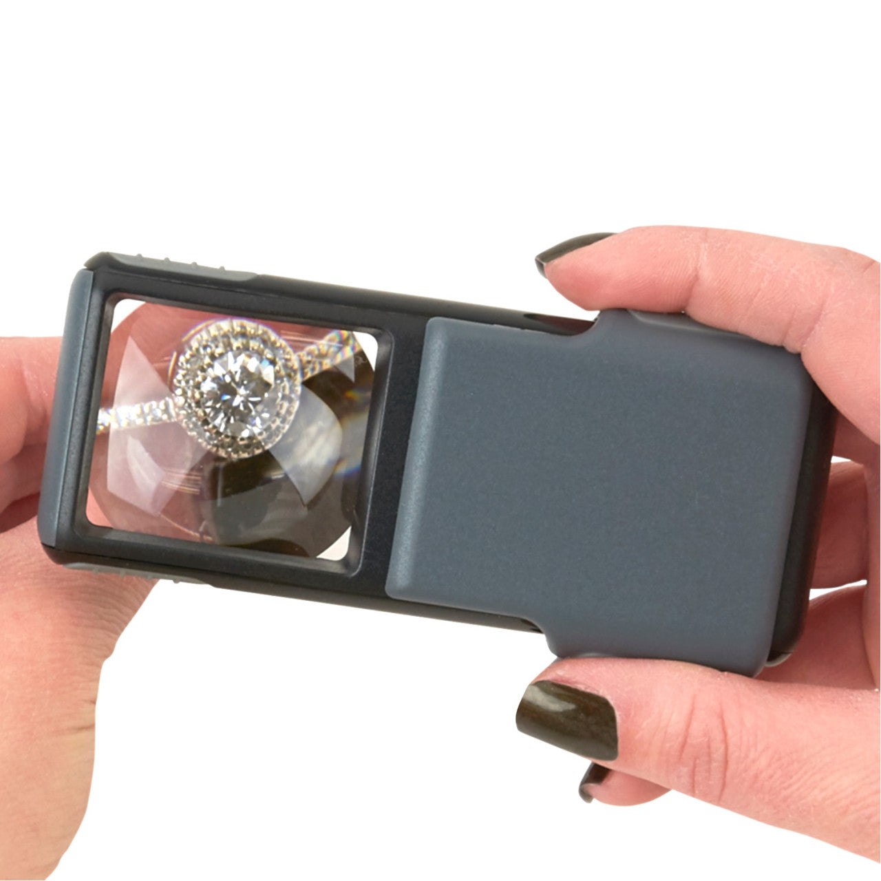 Eine Hand hält eine kompakte Bauweise Taschenlupe mit einer LED-Leuchte, um einen Diamantring genau zu untersuchen.