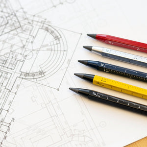 Fünf farbige Multitasking-Bleistifte mit nachhaltiger Endlosschreibspitze ruhen auf einem technischen Architekturentwurf und verleihen Ihrem Arbeitsplatz einen BAU-Look.
