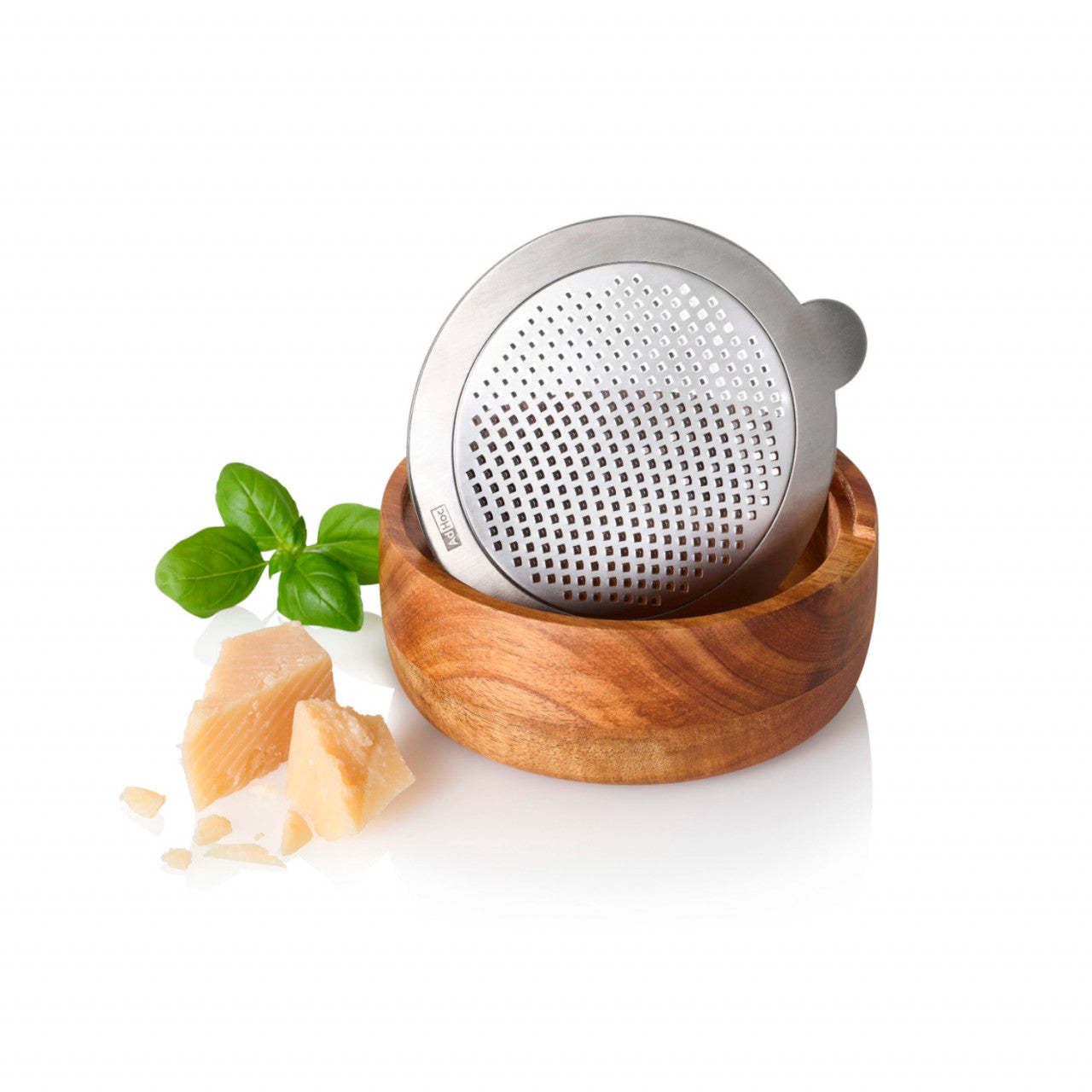 Runde Akazienholzschale mit einer PreciseGrate Feinreibe, Käsestücken und frischen Basilikumblättern auf weißem Hintergrund.