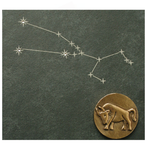 Zeichnung des Sternbilds Stier mit einer bronzenen Stiermünze und funkelnden Swarovski-Elementen, alles auf einem eleganten Naturschiefer. Ein einzigartiges Schmuckstück für jeden Sternzeichen-Liebhaber.