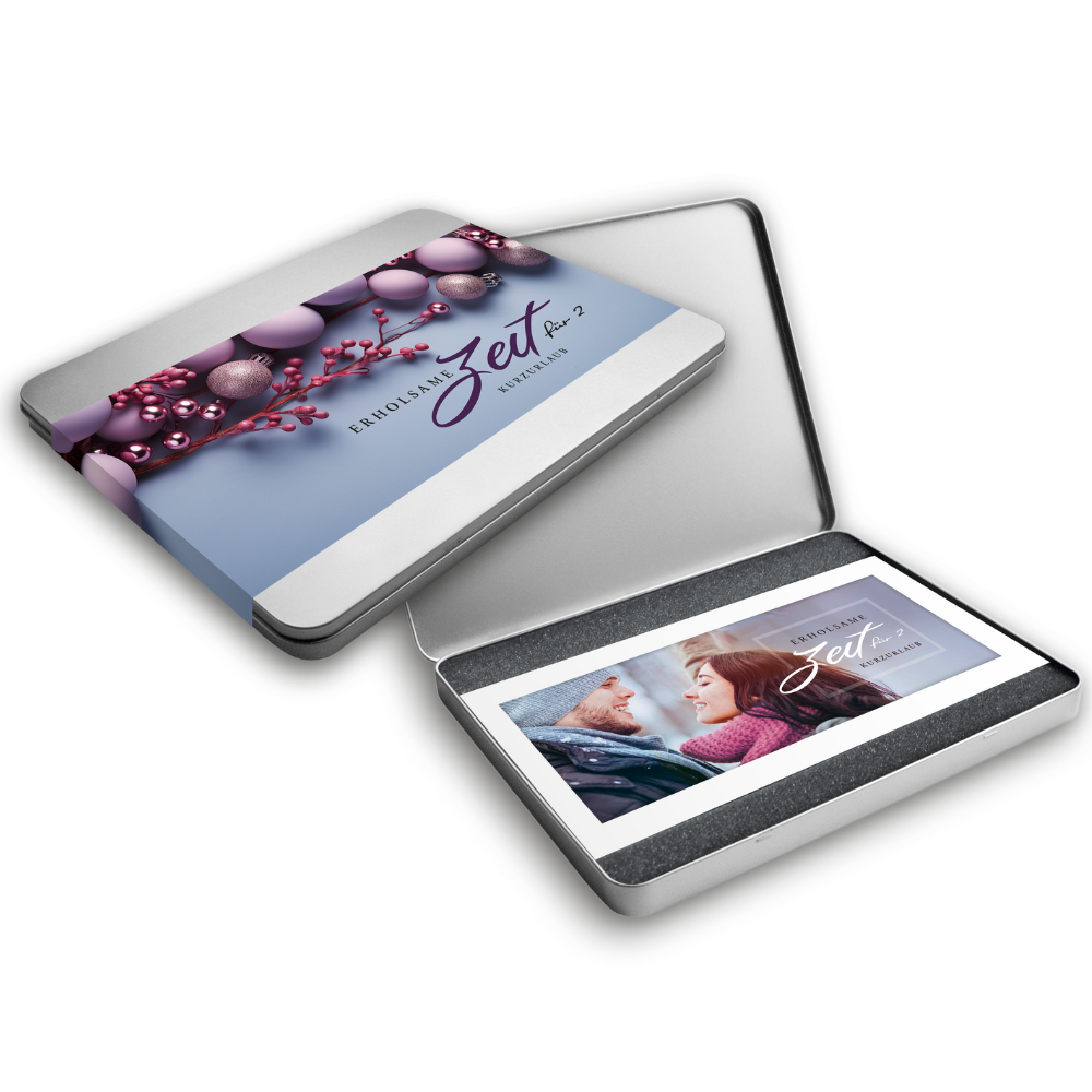 Geöffnete Metallbox in der ein Gutschein drin ist, auf dem ein Paar abgebildet ist. Daneben die Aufschrift "Erholsame Zeit". Daneben eine geschlossene Metallbox mit einem Deckel, auf dem ein lila-blaues Design mit Weihnachtskugeln und Beeren sowie dem Text "Erholsame Zeit für 2 – Kurzurlaub" abgebildet ist