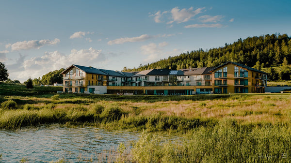 Ein großes Hotel befindet sich in einer abgelegenen Naturlage. Davor ist ein Teich. 