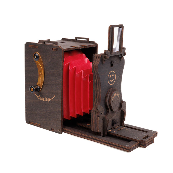 Eine kompliziert aussehende Kamera aus Holz mit einem roten Balg  Gravuren und einem kleinen Drehhebel an der Seite.
