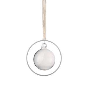 Klare Glaskugel als Ornament hängt in einem Metallring in Messingoptik an einem Band mit Text, vor weißem Hintergrund.