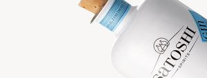 Eine Nahaufnahme einer weißen Flasche mit der Aufschrift „Satoshi Spirits London Dry Gin“ mit Korken und blauem Siegel, bekannt für seine Noten von toskanischem Wacholder.