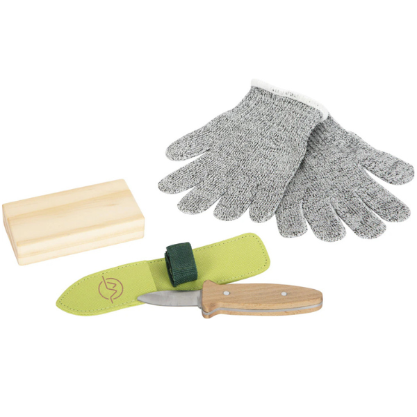 Schnittfeste Handschuhe, ein Outdoor-Kindermesser mit Holzgriff und Scheide sowie ein kleiner Holzblock sind auf weißem Hintergrund angeordnet.