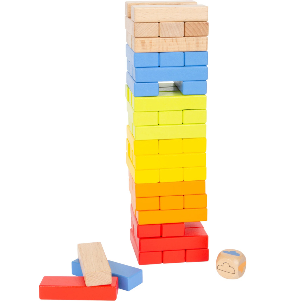 Ein gestapelter Turm aus bunten Holzklötzen in Regenbogenfarben steht neben einem Würfel und mehreren losen Teilen – perfekt für ein spannendes Wackelturm-Spiel Geschicklichkeitsspiel.
