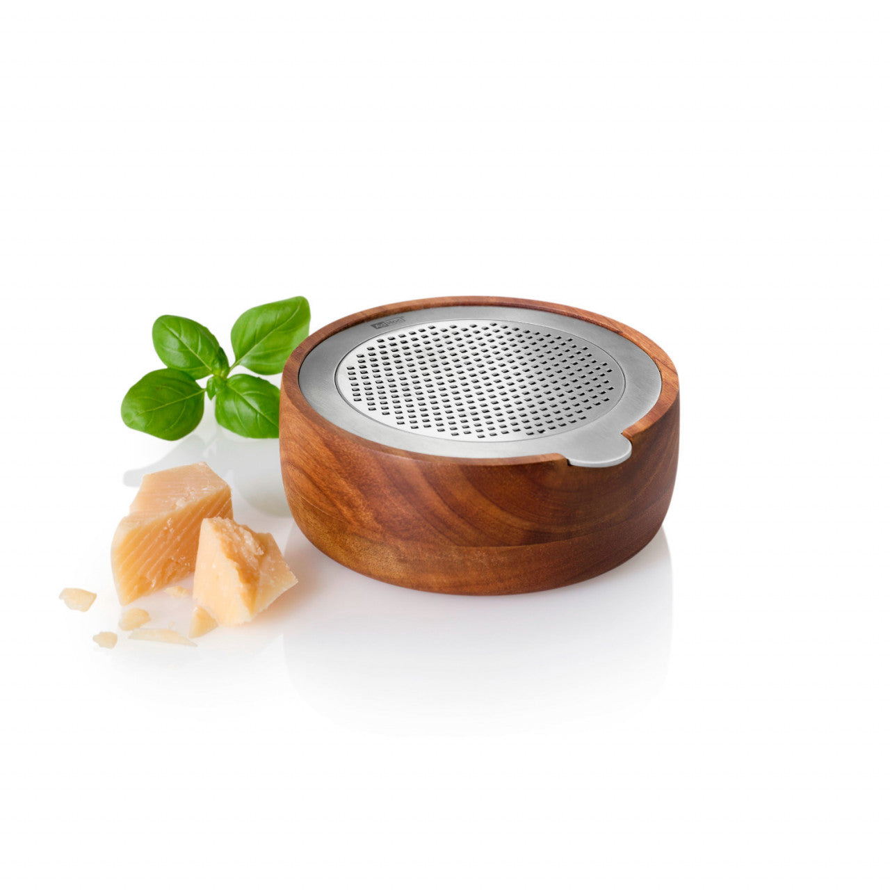 Feinreibe-Käsereibe aus Holz mit Metallkappe, Akazienholzgriff, Basilikumblättern und Parmesanstücken auf weißem Hintergrund.