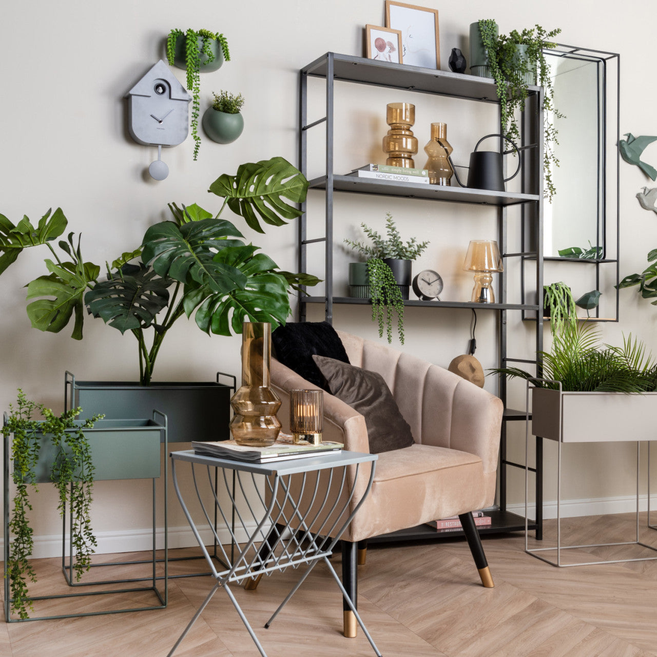 Modernes Wohnzimmer mit Pflanzen, beigem Sessel, Metallregalen, goldenem Dekor und einer an der Wand montierten modernen Kuckucksuhr für einen Hauch minimalistisches Design.