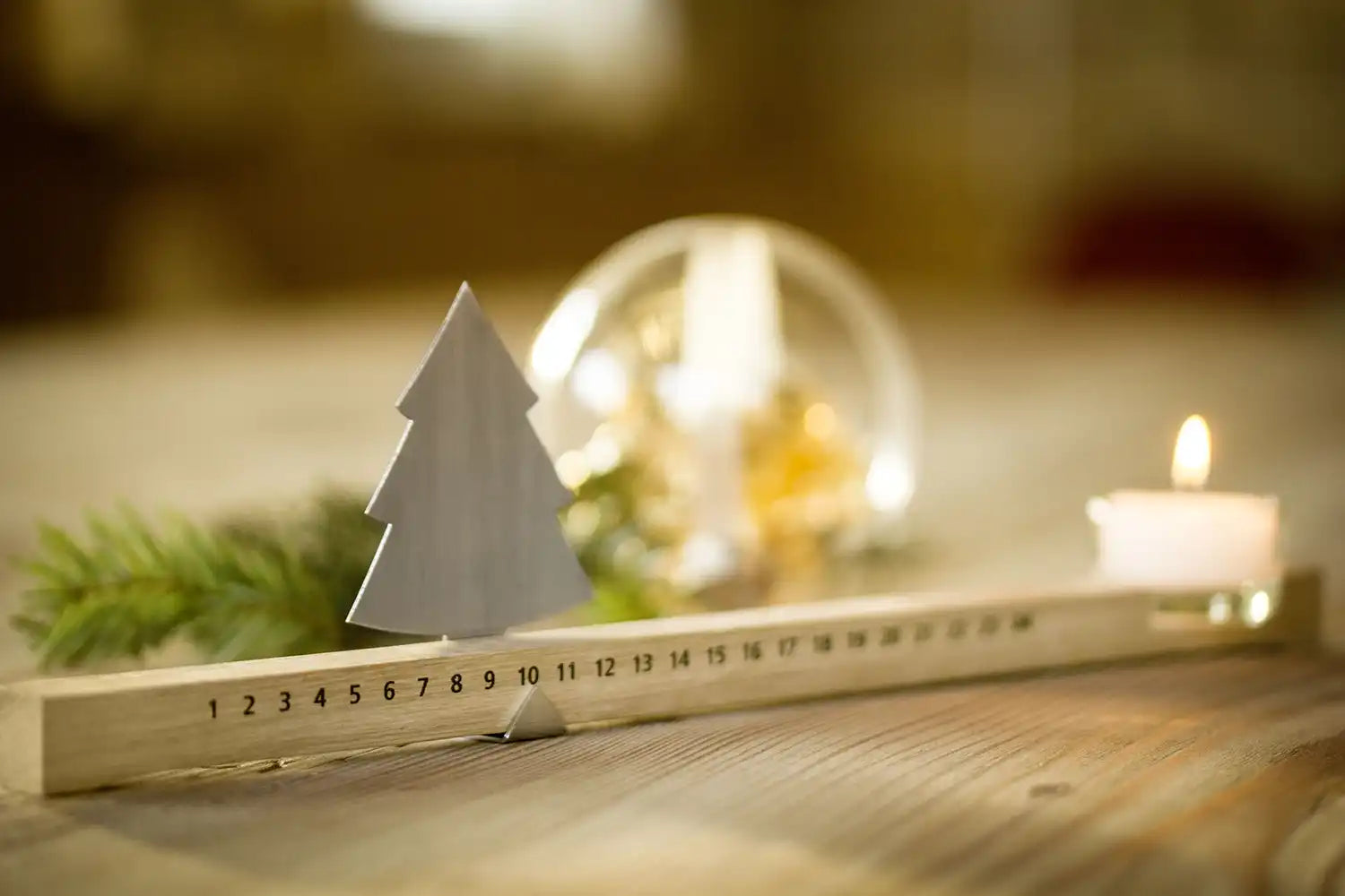 Adventsleiste mit Baum-, Kerzen- und Tannenzweigdekoration aus Metall.