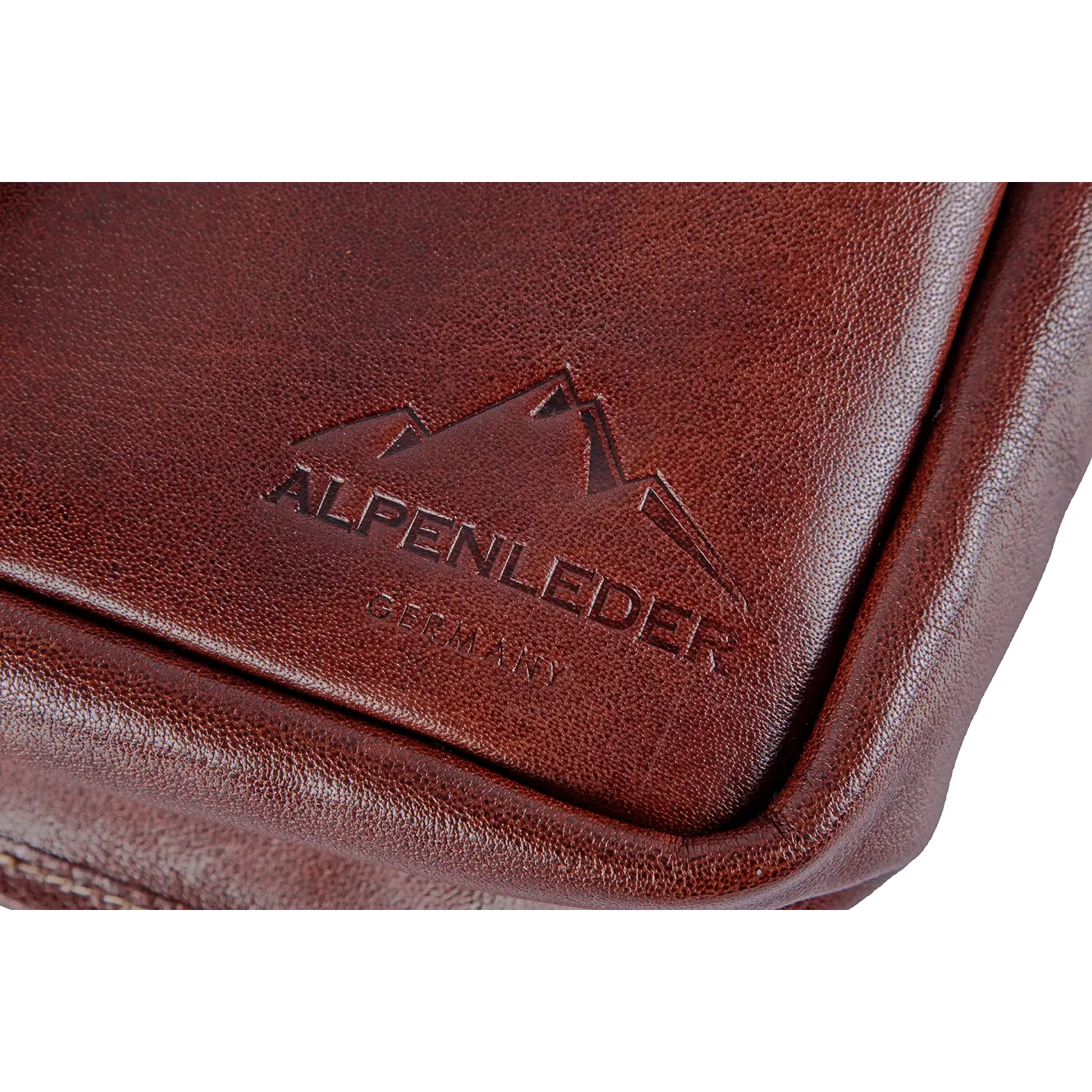 Nahaufnahme der Alpenleder Kameratasche PRESSE aus braunem Leder mit dem geprägten „ALPENLEDER GERMANY“-Logo und Bergmotiv. Perfekt für Hobbyfotografen: Die glatte Lederstruktur und die sichtbaren Kantennähte vereinen Funktionalität und Eleganz.