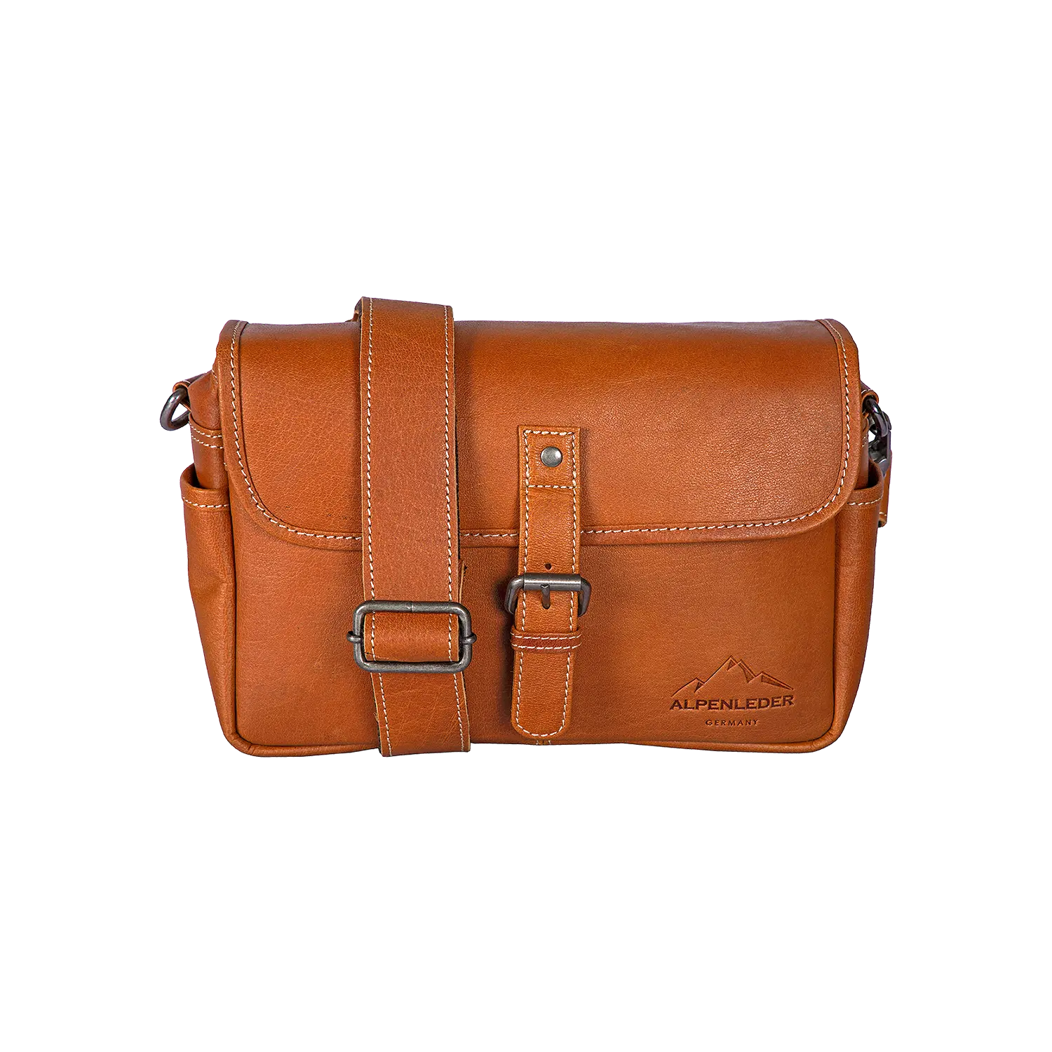 Die Alpenleder Kameratasche PRESSE ist eine braune Leder-Umhängetasche mit Klappe, Schnallenverschluss und verstellbarem Tragegurt. Sie ist speziell für Fotografen konzipiert und verfügt über eine Polsterung zur sicheren Befestigung der Kamera. Das Logo mit Bergprägung „Alpenleder“ ist ebenfalls eingeprägt.