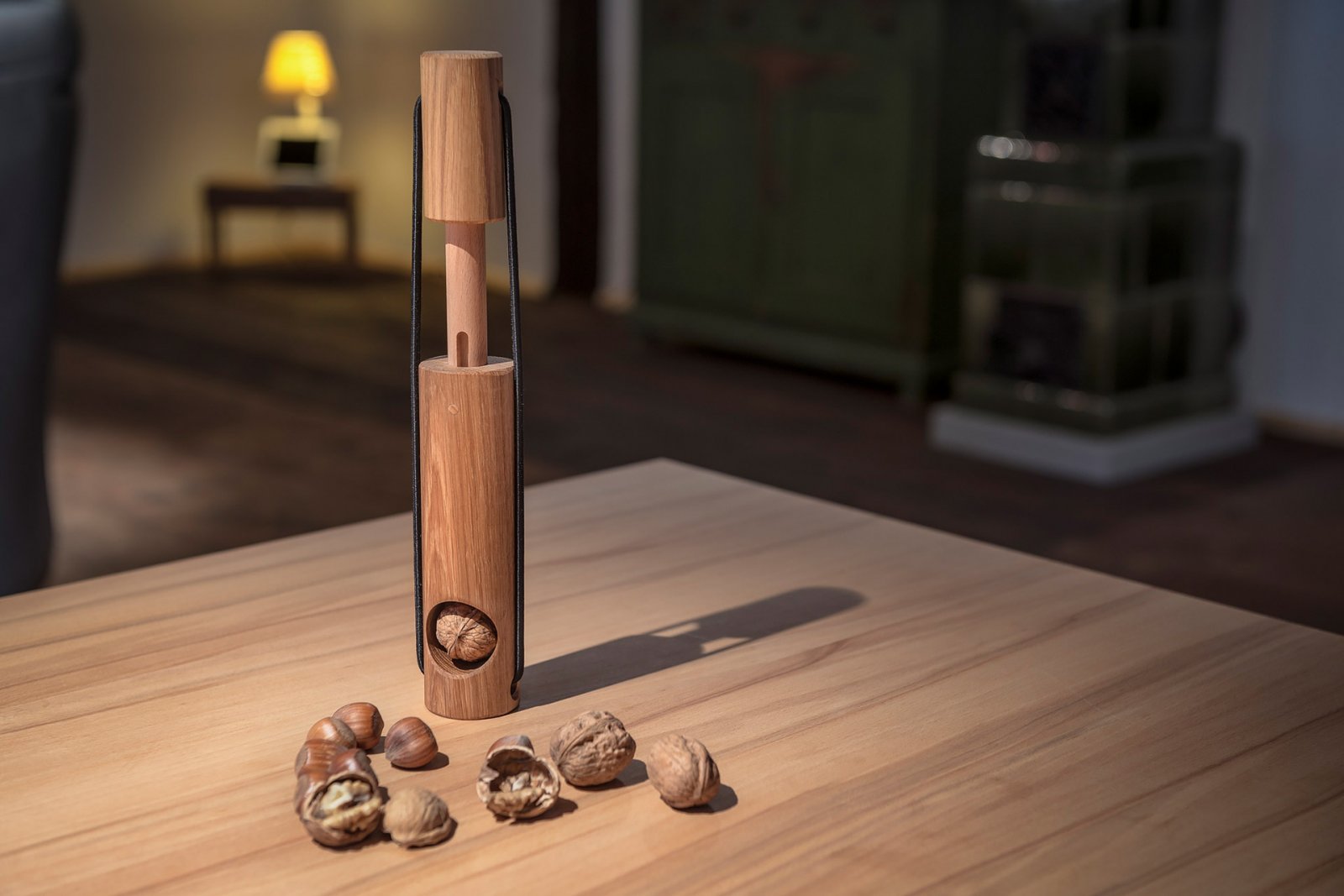 Ein handgefertigter Nussknacker aus Eichenholz und mehrere geknackte und ganze Nüsse liegen auf einem Holztisch in einem gemütlichen Raum.