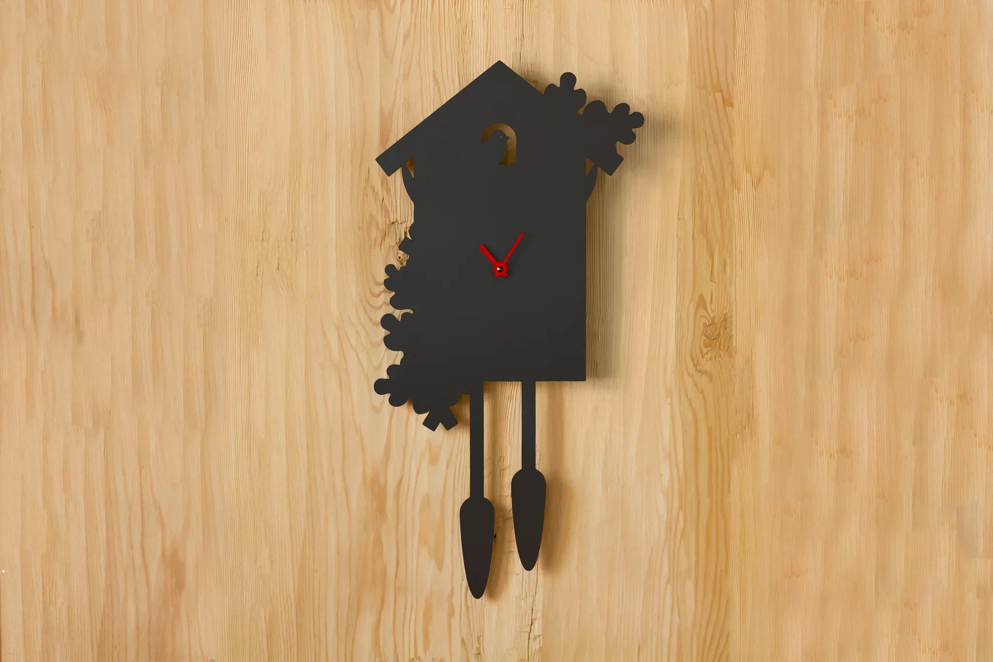 Schwarze moderne Kuckucksuhr mit roten Zeigern hängt an einer hellen Holzwand; es ist 10:10 Uhr – ein perfekter Akzent für moderne Einrichtungen und Liebhaber zeitlosen Designs.
