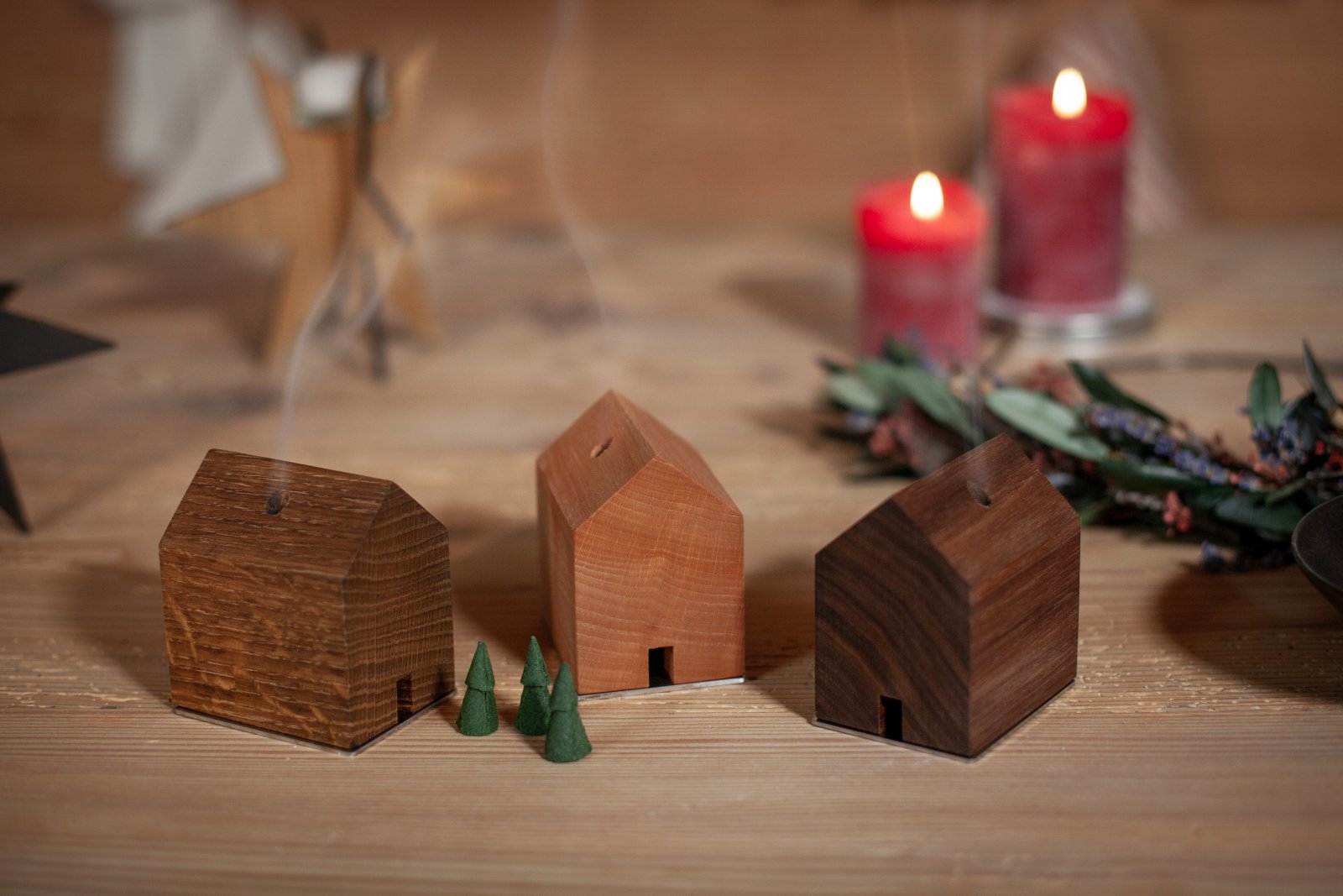 Drei Räucherstäbchenhalter in Holzhausform von Designer Jan Hartmann erinnern an den Charme der Schwarzwaldhöfe. Neben Kerzen und Weihnachtsdeko steigt Rauch von grünen Räucherkegeln auf und sorgt für eine festliche RÄUCHERMÄNNCHEN-RAUCHHAUS-Atmosphäre.