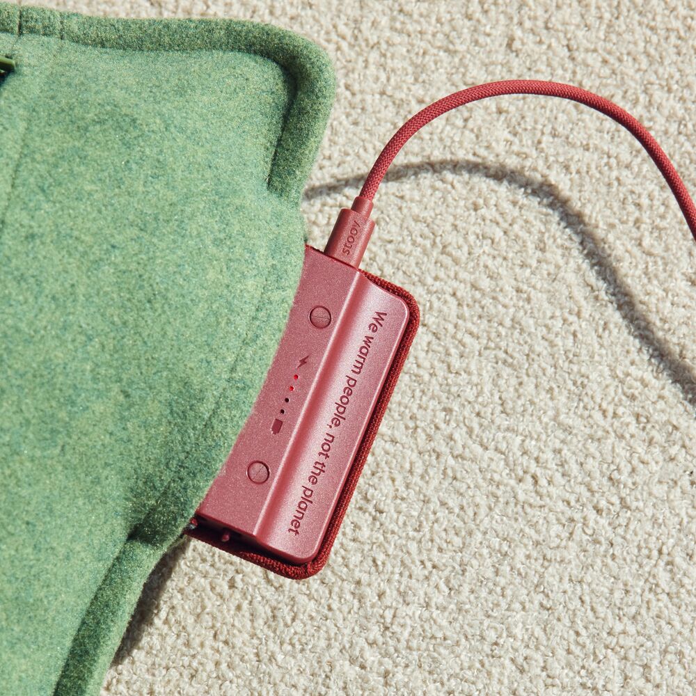 Eine rote Powerbank versorgt einen Ploov Original Flex grau auf Stoff.
