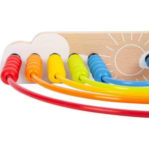 Nahaufnahme von bunten Perlen auf gebogenen Drähten einer hölzernen Motorikschleife, angeordnet in einem Regenbogenmuster – eine bezaubernde Kinderzimmerdekoration und praktisches Lernspielzeug.