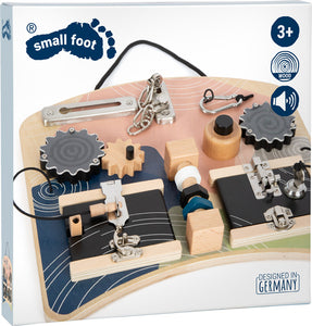 Lernbrett aus Holz mit Zahnrädern, Schlössern und Knöpfen für Kinder, inspiriert von der Montessori-Pädagogik. Beschriftet mit small foot, ab 3 Jahren, Deutschland.