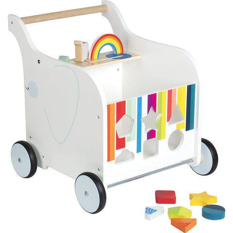 Lauflernwagen aus Holz mit gummierten Rädern, buntem Formensortierer, Regenbogenteilen und losen geometrischen Blöcken auf dem Boden für Spiel- und Lernspaß.