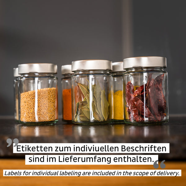 Vier Gläser mit silbernen Deckeln, gefüllt mit Senfkörnern, Gewürzen und Chilischoten, stehen als stilvolle Staulösung mit Magnetkraft ordentlich auf der Küchenarbeitsplatte.