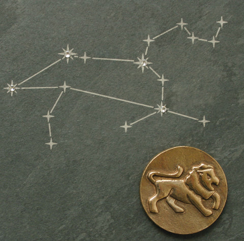Eine Zeichnung des Sternzeichens Löwe über einer Löwenmünze, veredelt mit Swarovski-Elementen
