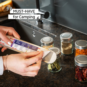 Nahaufnahme von Händen, die ein Mehrzweckwerkzeug neben Gewürzgläsern auf einer Küchentheke verwenden und dessen Magnetkraft zur Schau stellen – ein Muss fürs Camping.