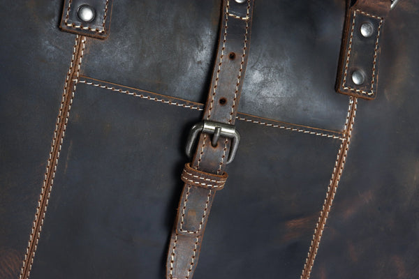 Nahaufnahme einer dunkelbraunen Aktentasche LUDWIG aus Büffelleder mit sichtbaren Nähten, einem Schnallenriemen und in vegetabiler Gerbung gefertigt.